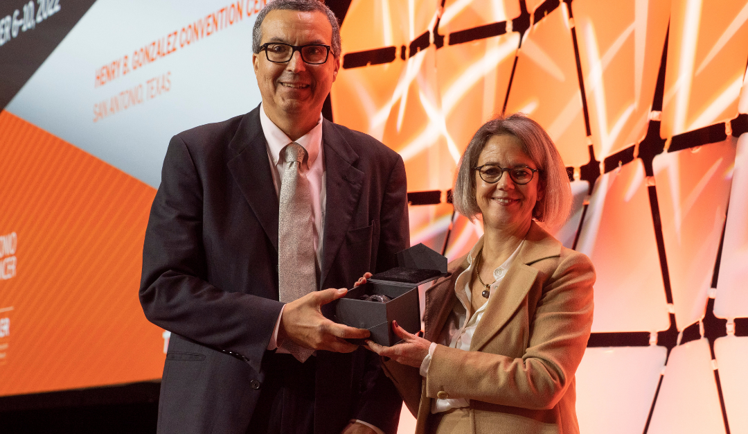 dr. chuck perou holds his brinker award on a stage at sabcs 