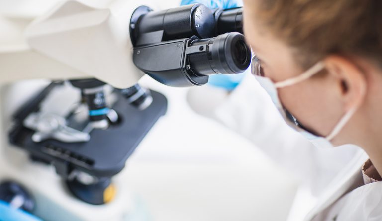 scientist looks at a microscope up close