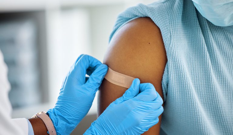 a doctor administers a bandage on a female patient after a shot