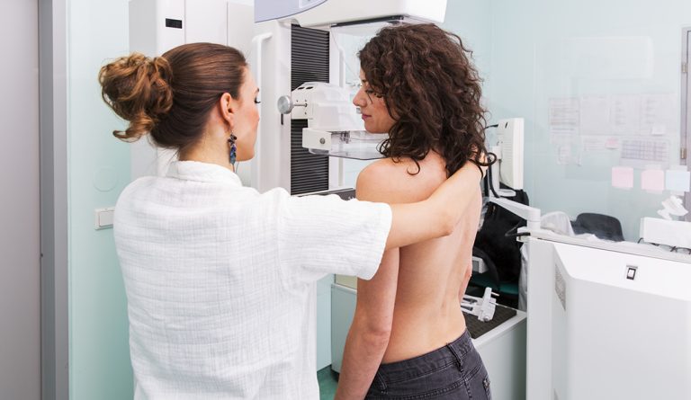 A Medtech assessing a woman for a mammogram