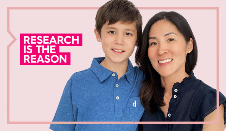 Marianne and her son smile at the camera against a light pink background