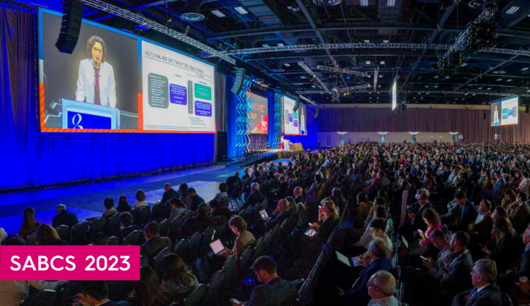 a panoramic shot of the main room at SABCS showing hundreds of people watching a researcher speak on stage