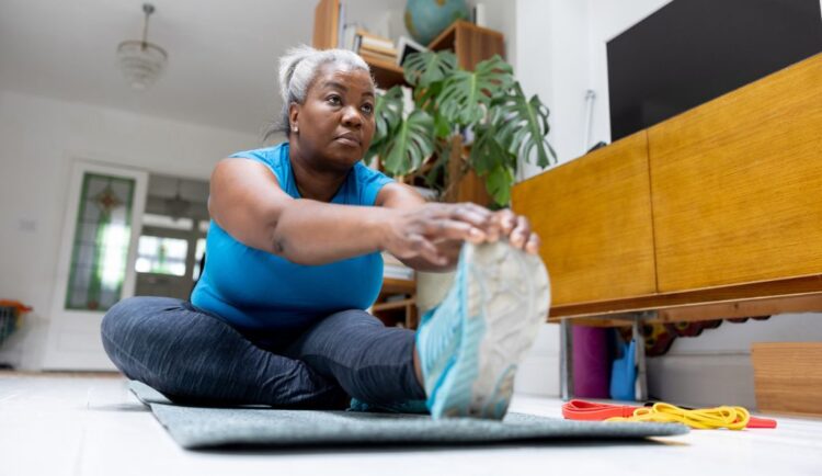 An older woman stretches on an exercise mat at home