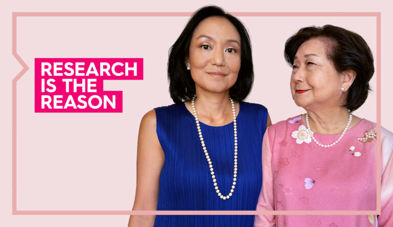 a portrait of keiko and tomomi standing next to each other smiling against a light pink background