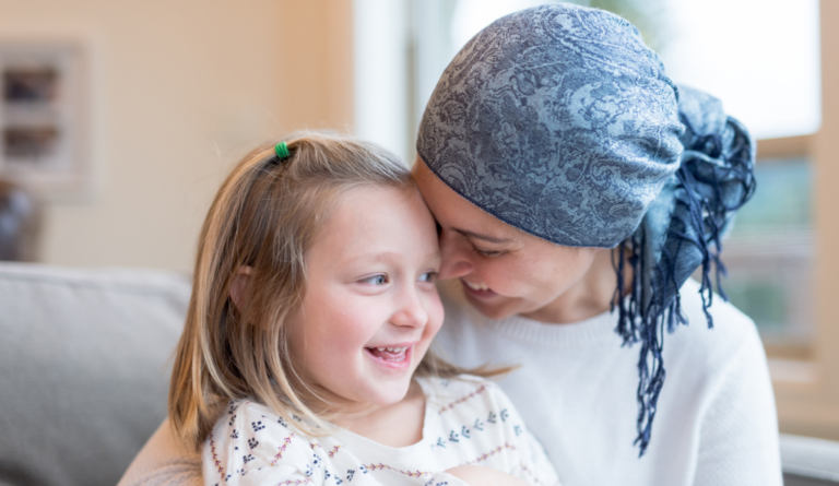 A smiling young woman in a headscarf sitting with a laughing little girl.