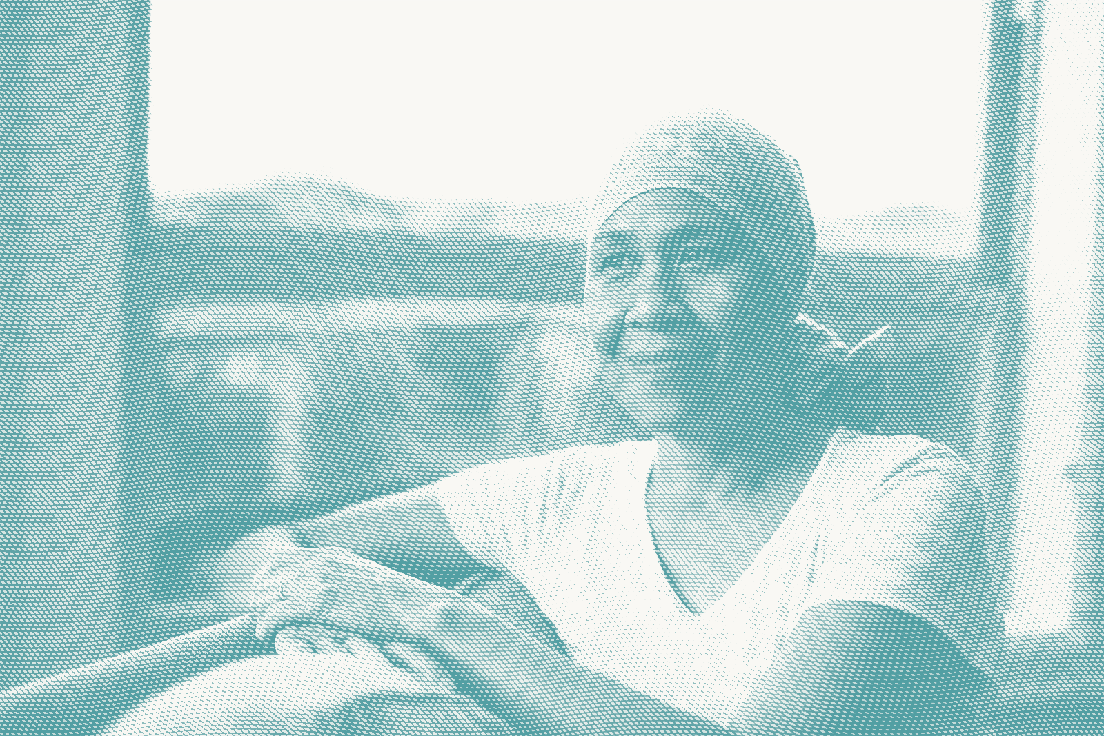 an older woman sits next to a window. she's wearing a headscarf as she's lost her hair after chemotherapy for breast cancer