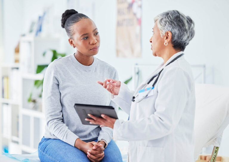 A doctor holding a tablet talking to a patient