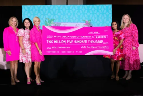 zeta tau alpha women dressed in pink holding a large pink check for 2.5 million dollars to BCRF