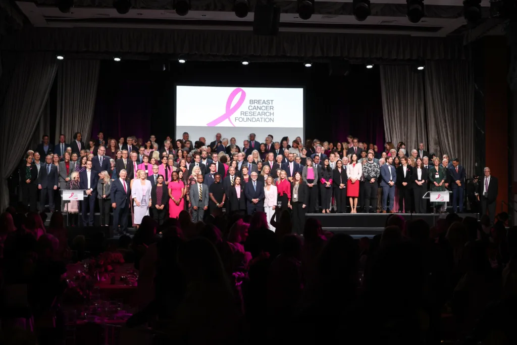 over 200 breast cancer research foundation researchers standing on stage at the 2026 symposium