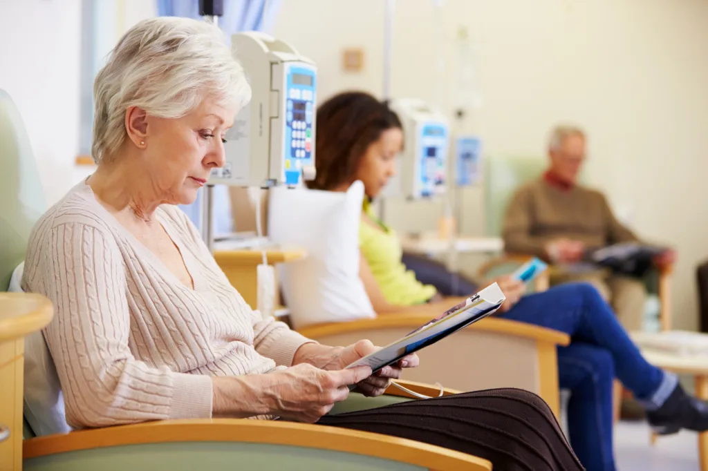 older white woman getting chemotherapy while filling out a form on a clopboard